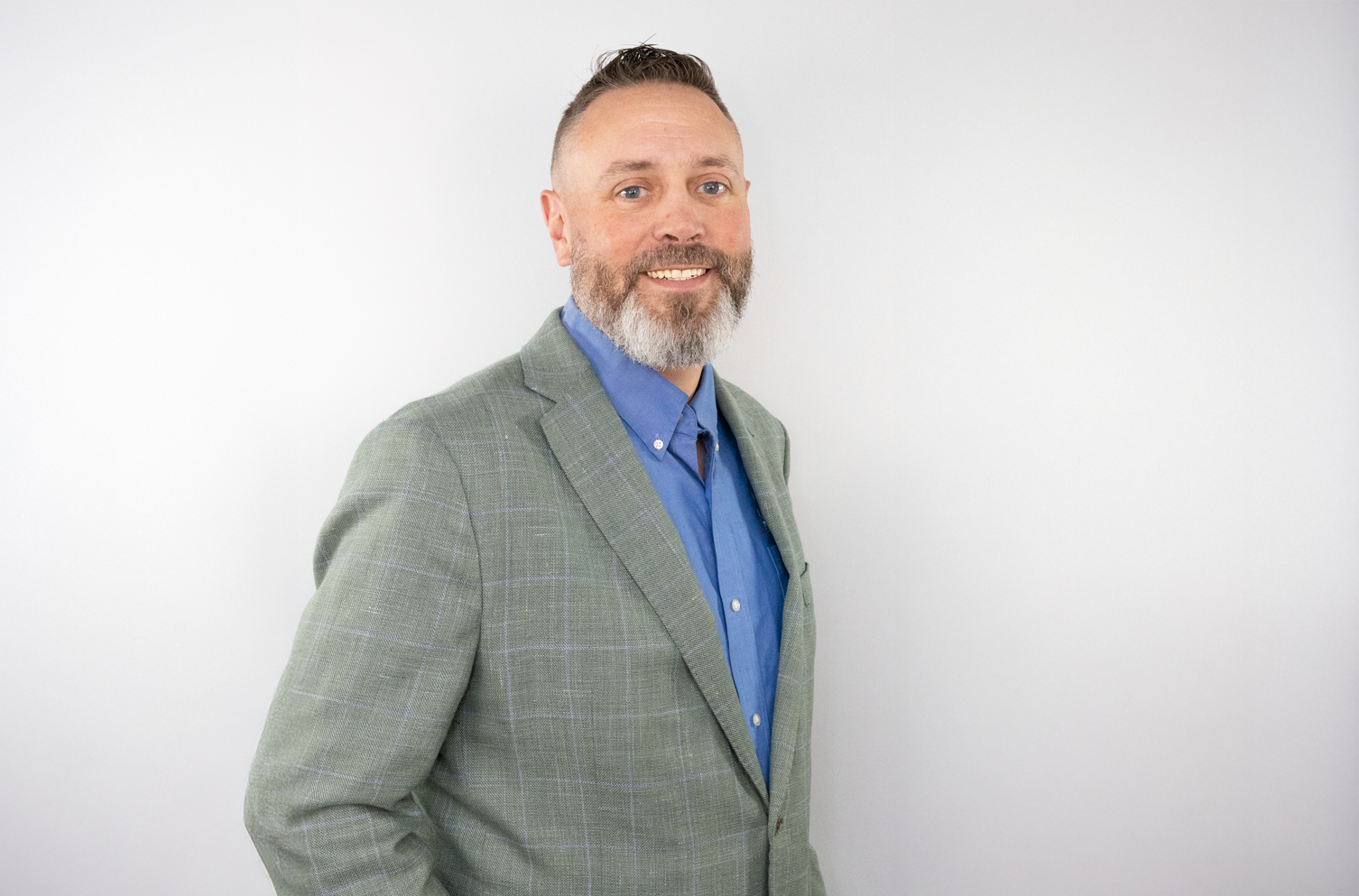 headshot image of FrankCrum Chief Information Security Officer Michael Webb smiling in a gray suit jacket, with a blue shirt, in front of a light gray background